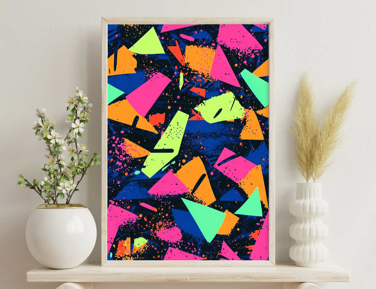 Vibrant abstract composition of overlapping triangular shapes in bold colors like orange, pink, blue, and green, with splashes and splatters against a dark background creating an energetic and dynamic effect.