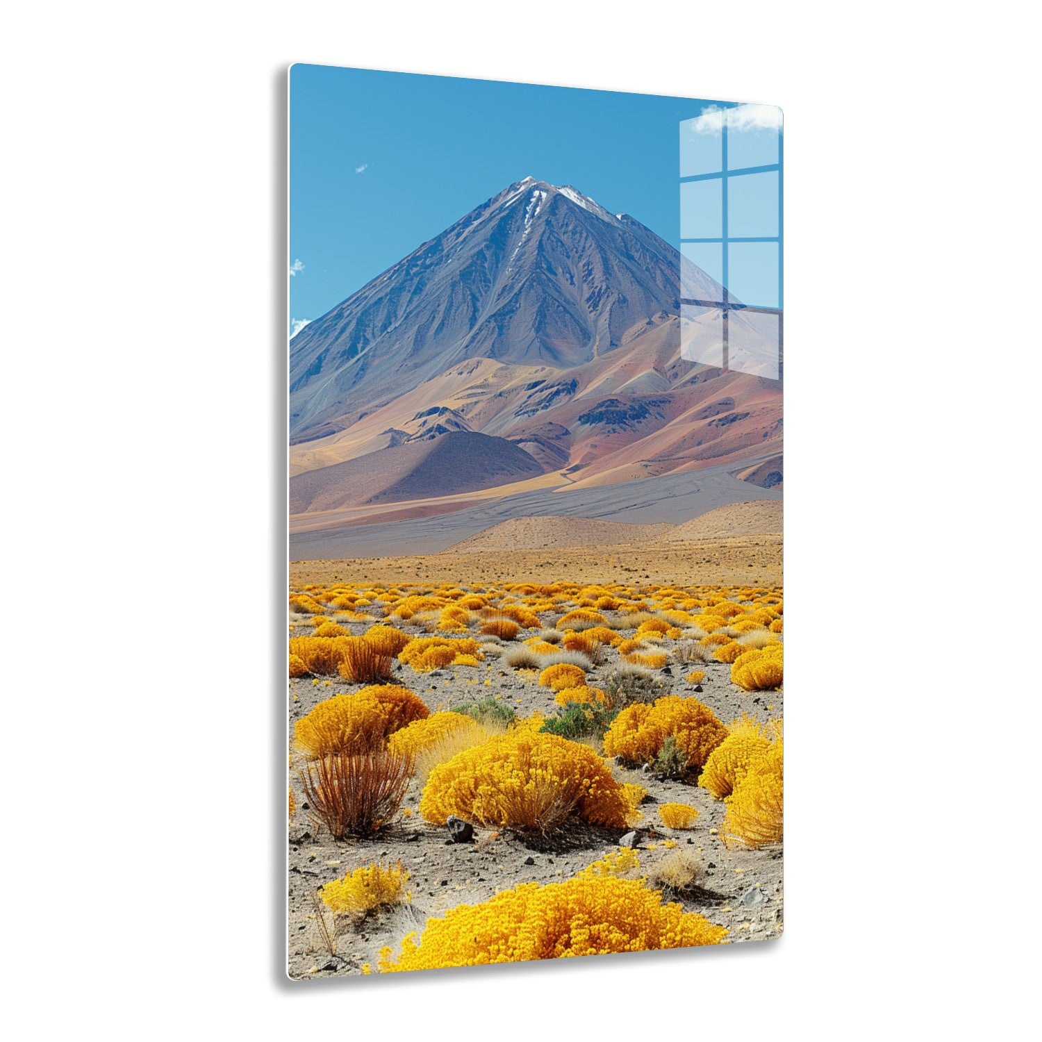 A majestic snow-capped mountain rises against a vivid blue sky, surrounded by a vast landscape of undulating hills and shrubs with vibrant yellow and rusty hues in the foreground.
