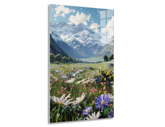 Scenic view of majestic snow-capped mountains towering over a vibrant alpine meadow blanketed with a profusion of colorful wildflowers in full bloom under a blue sky with fluffy white clouds.
