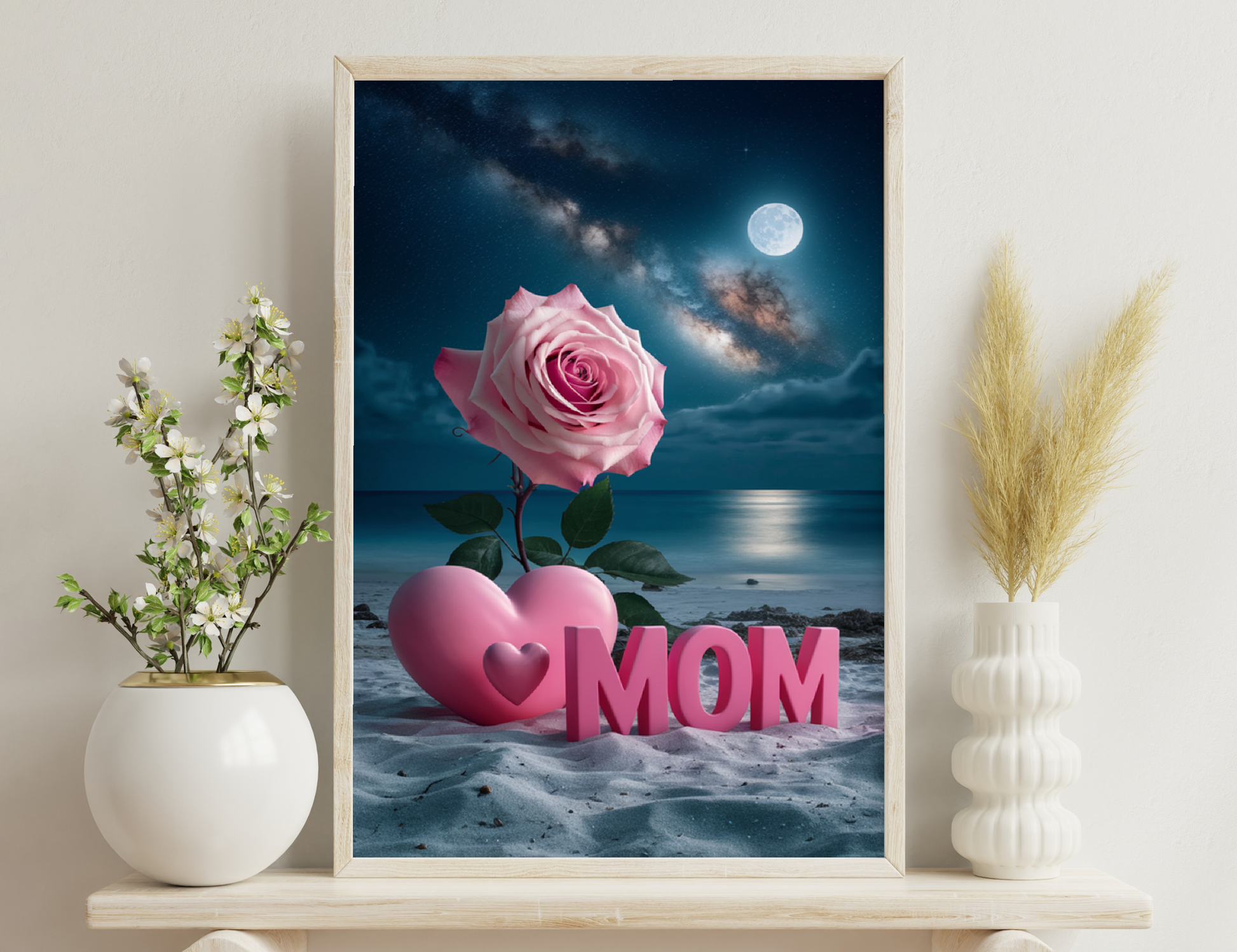 A pink rose and pink heart with "MOM" text against a scenic night sky with a full moon and Milky Way over a peaceful ocean, for a Mother's Day theme.
