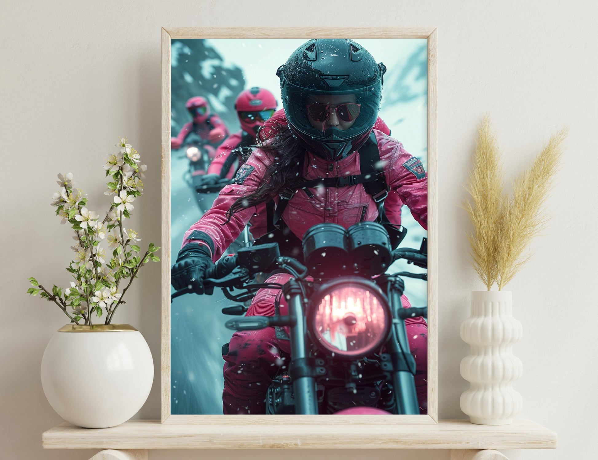 Snow-covered motorcyclists in bright pink insulated suits and helmets riding powerful bikes in wintry conditions. The focused rider in the foreground grips the handlebar tightly as snow flurries swirl around them.
