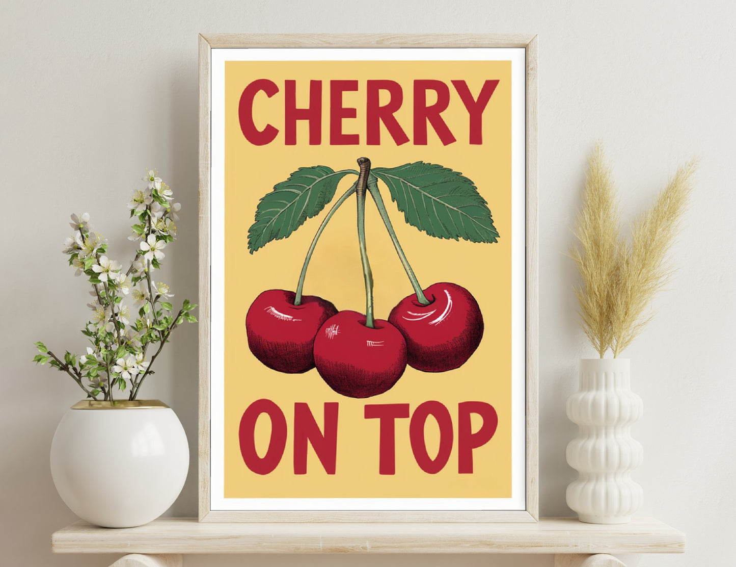 Cherry illustration with three red cherries with green leaves on a tan background, text reads "CHERRY ON TOP" in red capital letters.

