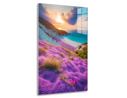 A stunning sunset view of a beach cove surrounded by vibrant purple flowering plants on the slopes, with turquoise water, snow-capped mountains, and dramatic clouds in the sky.
