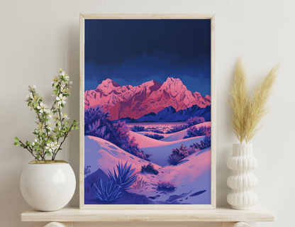 Scenic view of snow-covered desert landscape with vibrant pink mountains against deep blue sky, featuring sagebrush and yucca plants in foreground.
