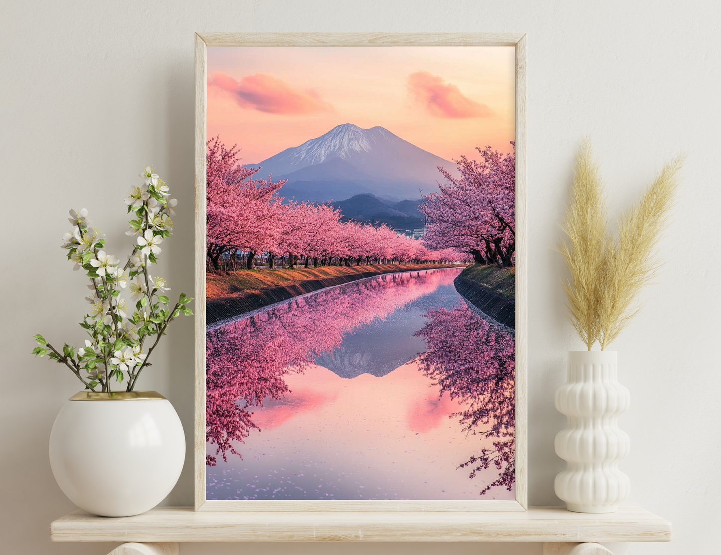Mount Fuji framed by blooming cherry trees reflecting in a still lake at sunset.
