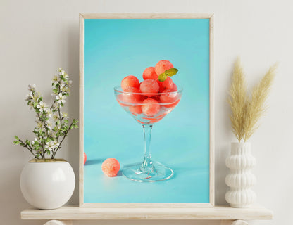 A glass bowl filled with ripe, juicy watermelon balls garnished with a mint leaf, against a blue background.
