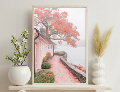 A winding pathway flanked by a stone wall leads to a small pink cottage nestled under a vibrant red tree in full autumn bloom, creating a serene and picturesque scene.
