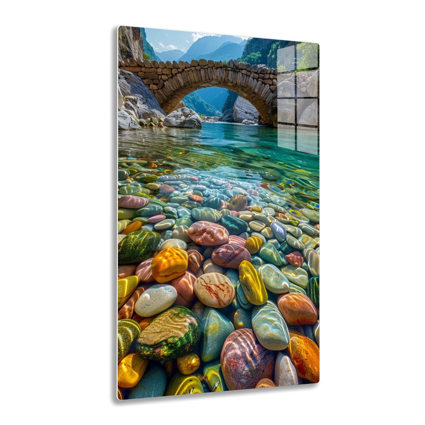 A beautiful stone bridge arches over a crystal-clear river running through a mountainous gorge, with the riverbed covered in smooth, colorful pebbles that create a mesmerizing pattern of vibrant colors and natural textures.
