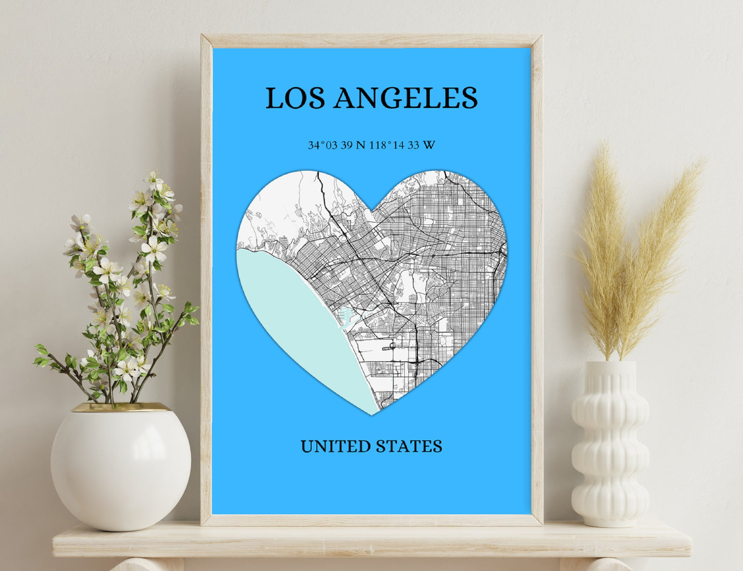 Alt text: A heart-shaped map of Los Angeles, with the street map covering the right side and the topographical map showing the mountains on the left. The city's coordinates and location are provided below the image.
