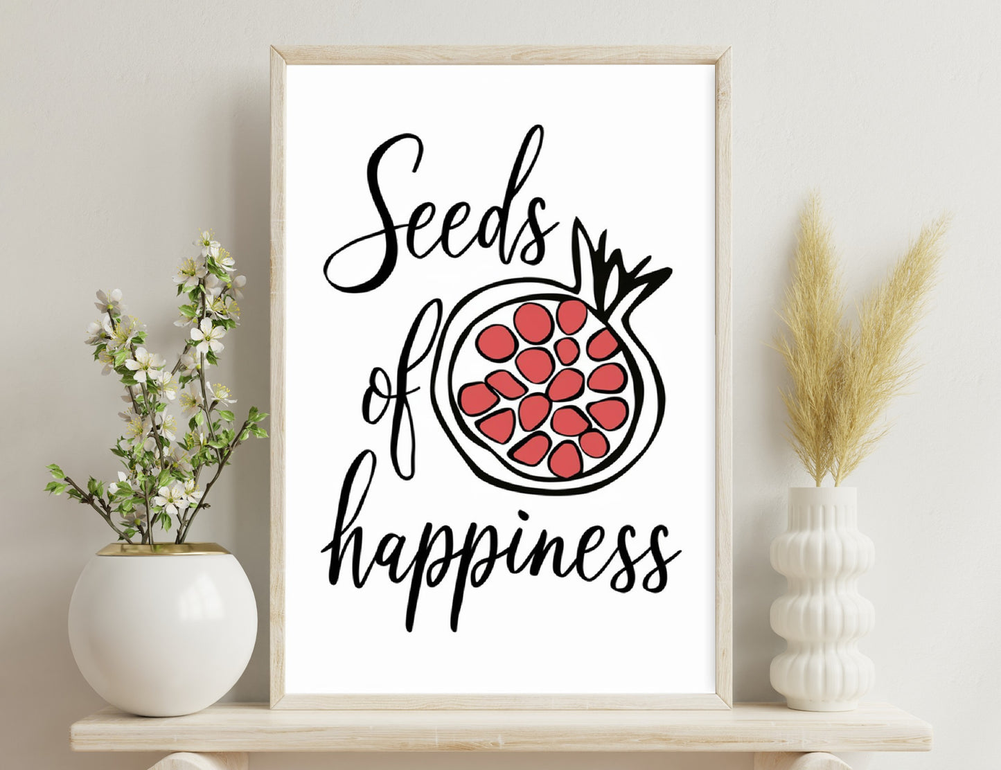 A sketched pomegranate illustration with the text "Seeds of happiness" written in a cursive style.
