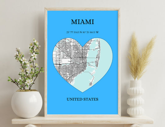 Miami city map in the shape of a heart against a blue background, showing street grids and coastlines with geographic coordinates. The text "MIAMI" and "UNITED STATES" frames the heart-shaped map image.
