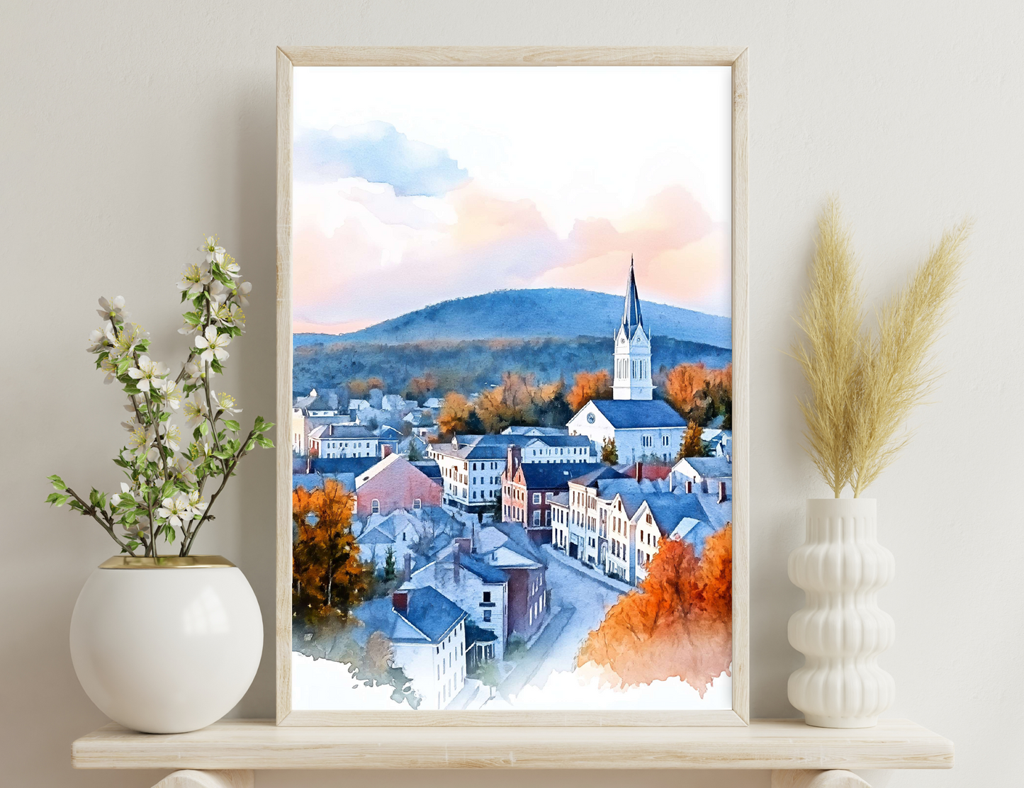 A watercolor painting depicting a picturesque town nestled in a mountainous landscape, with colorful fall foliage, a church steeple towering above the buildings, and wispy clouds in the sky.
