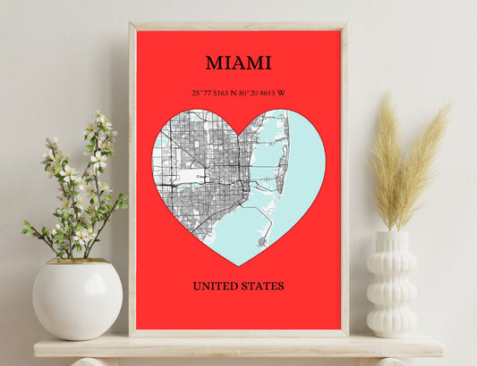 A red background poster featuring a heart shape formed by the street map of Miami on one side and the coastal outlines on the other, along with the city's name, geographic coordinates, and country.
