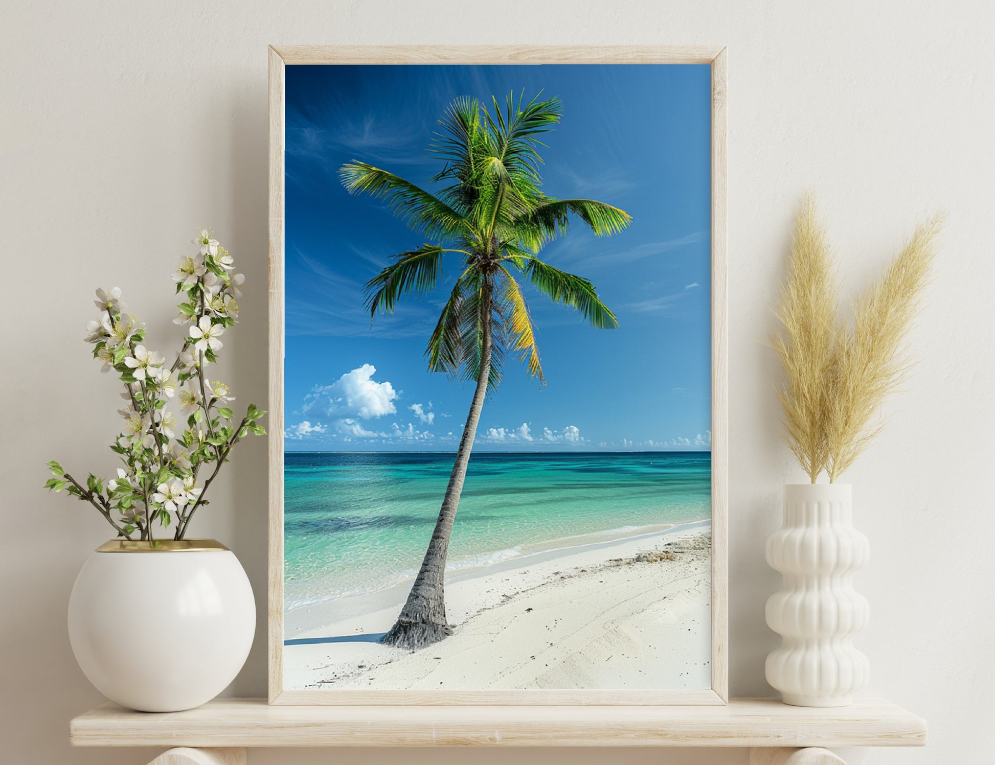 A tall, lush palm tree stands on a pristine white sandy beach, overlooking stunning turquoise waters under a blue sky with fluffy white clouds.
